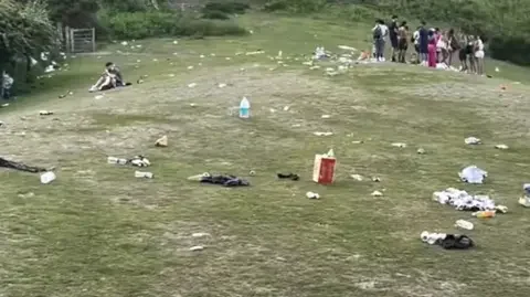 Rubbish on grass and people in the distance