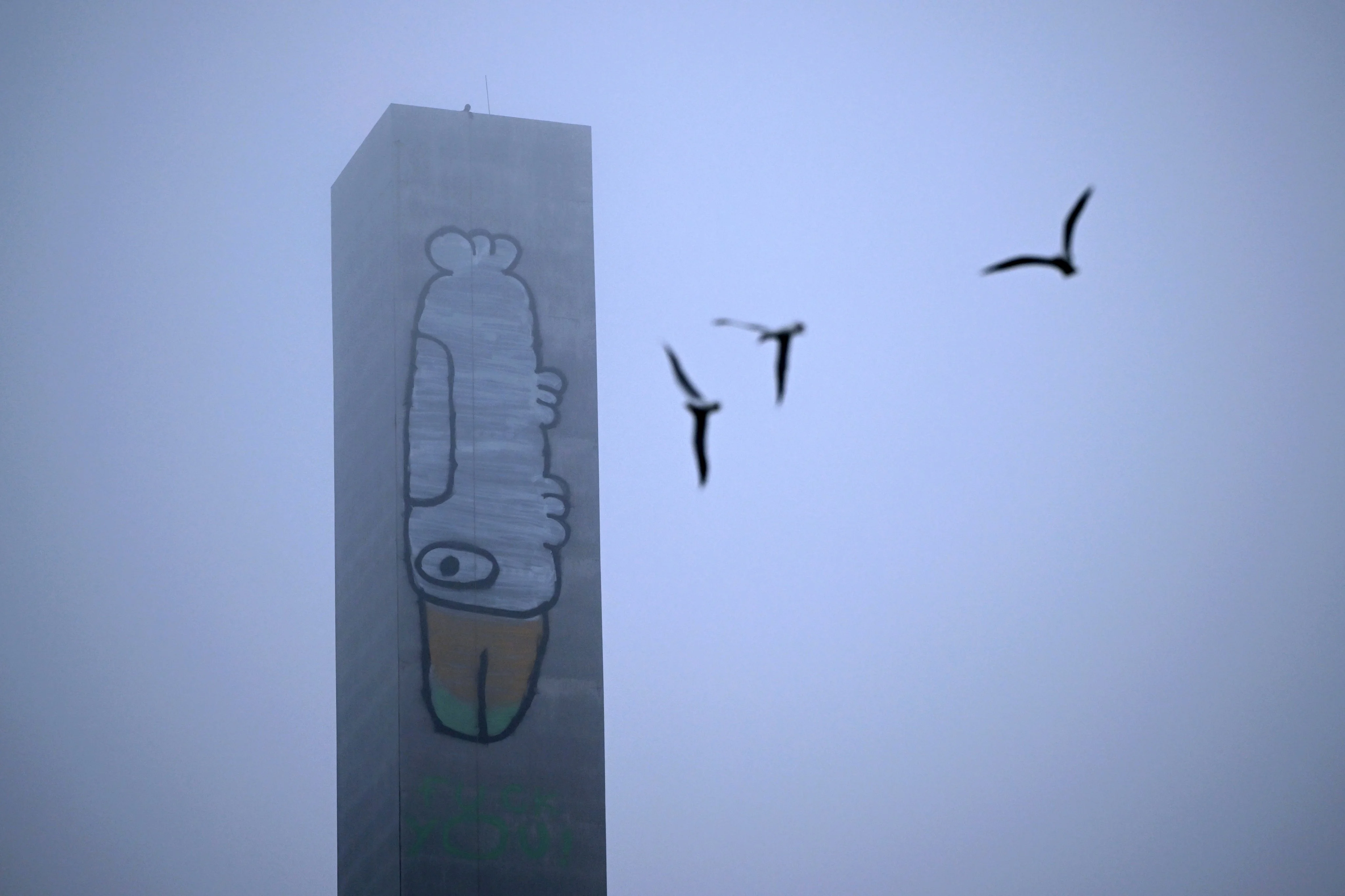 A man stands on top of the graffitied eastern pylon of the Bolte Bridge in Melbourne on Tuesday. Photo: EPA
