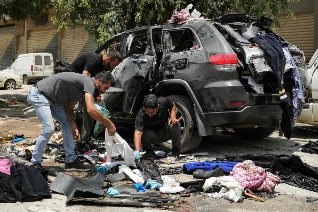 First responders inspect the wreckage of a car reportedly targeted by an Israeli strike in Nabatieh, Lebanon on Monday. Photo: AFP