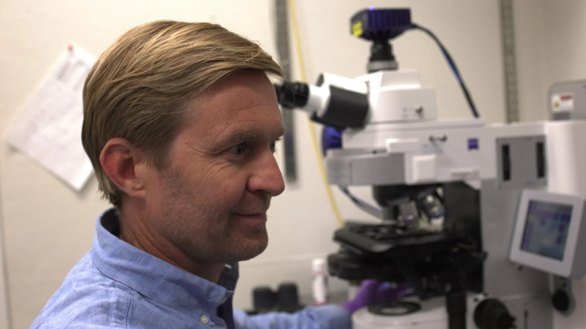 A man looks at a computer near a microscope