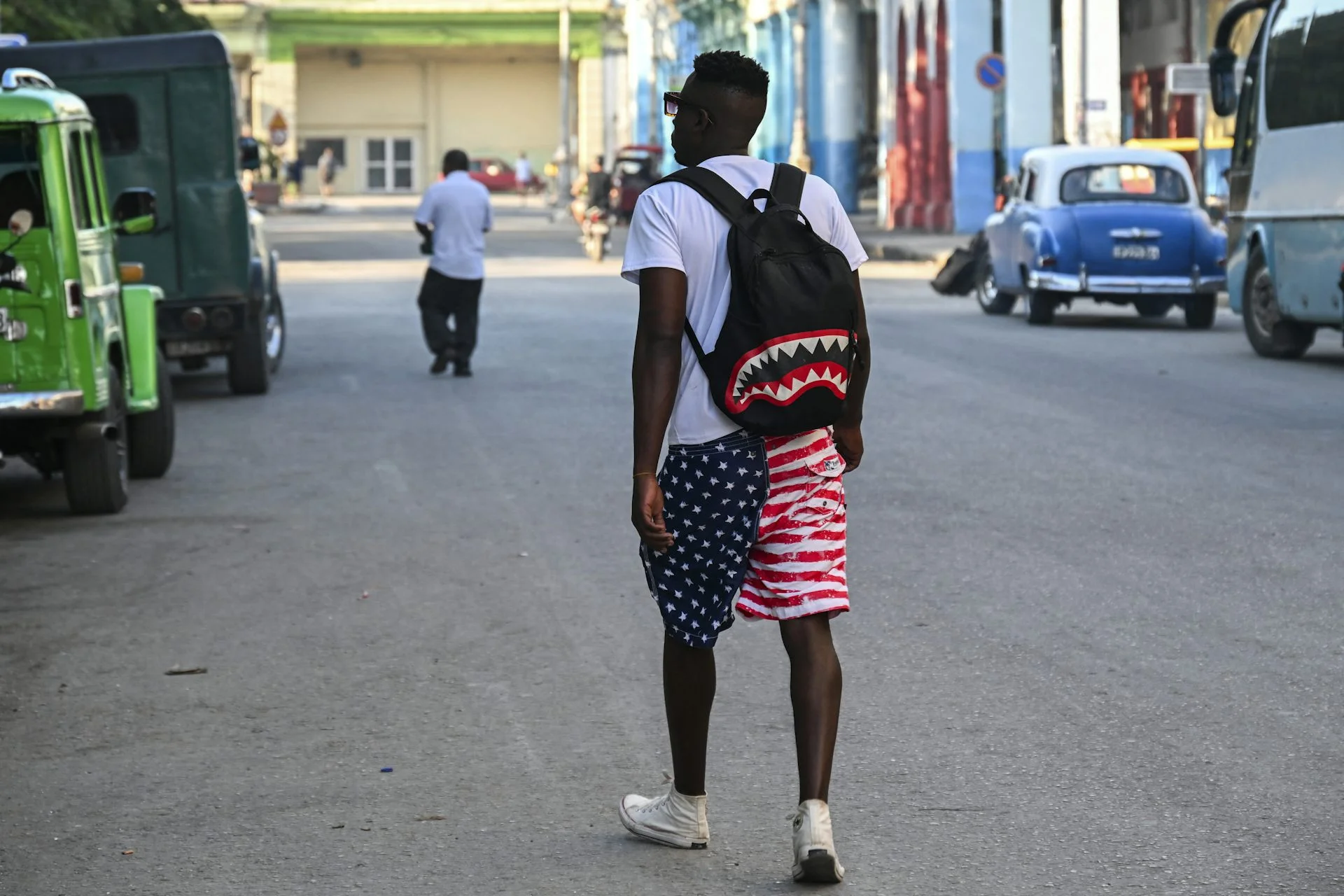 A man wears a backpack and red, white and blue shorts.