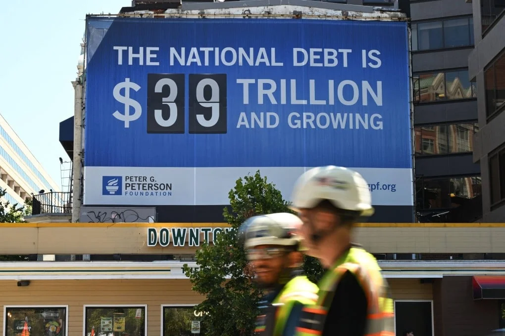 People pass in front of a billboard showing the US national debt in Washington on Wednesday. Photo: AFP