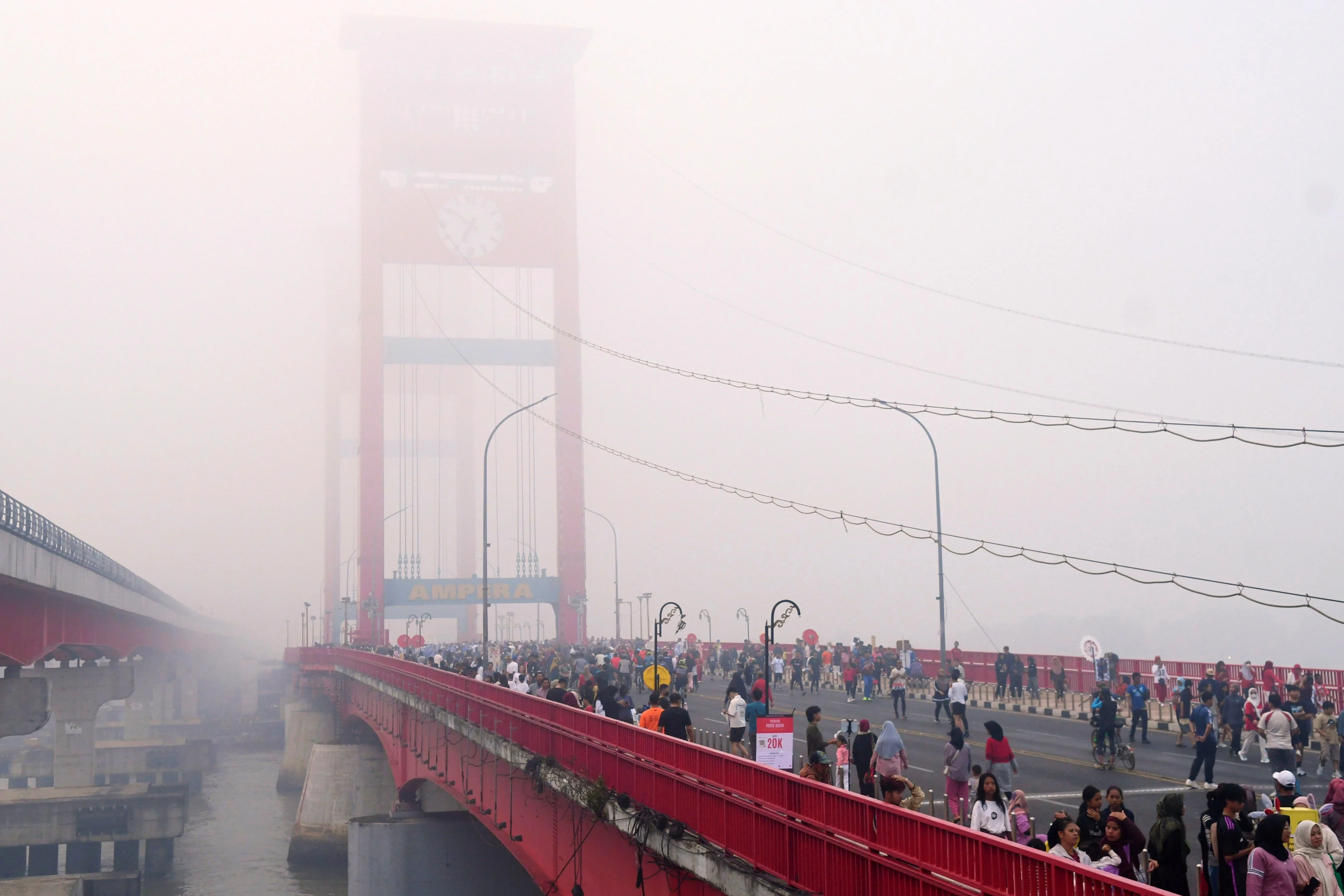 People walk along the Ampera Bridge as haze from wildfires blankets the city of Palembang in South Sumatra on Sunday. Photo: AP