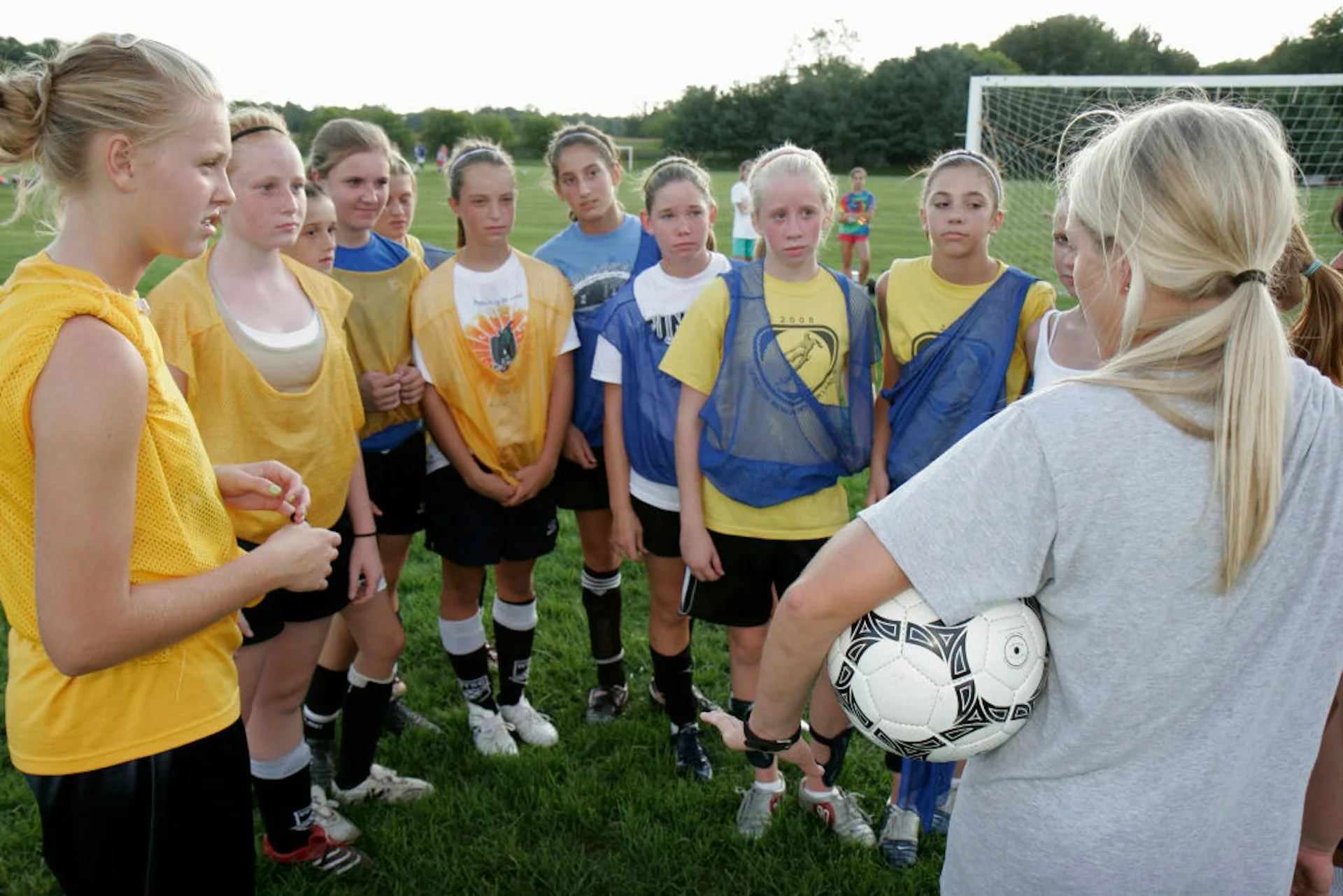 A group of girls on a soccer team listen to their coach.
