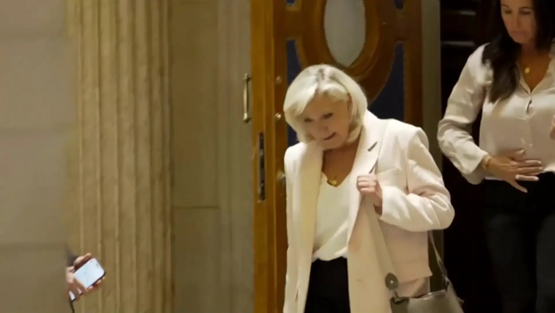 Marine Le Pen surrounded by her lawyers as she leaves court