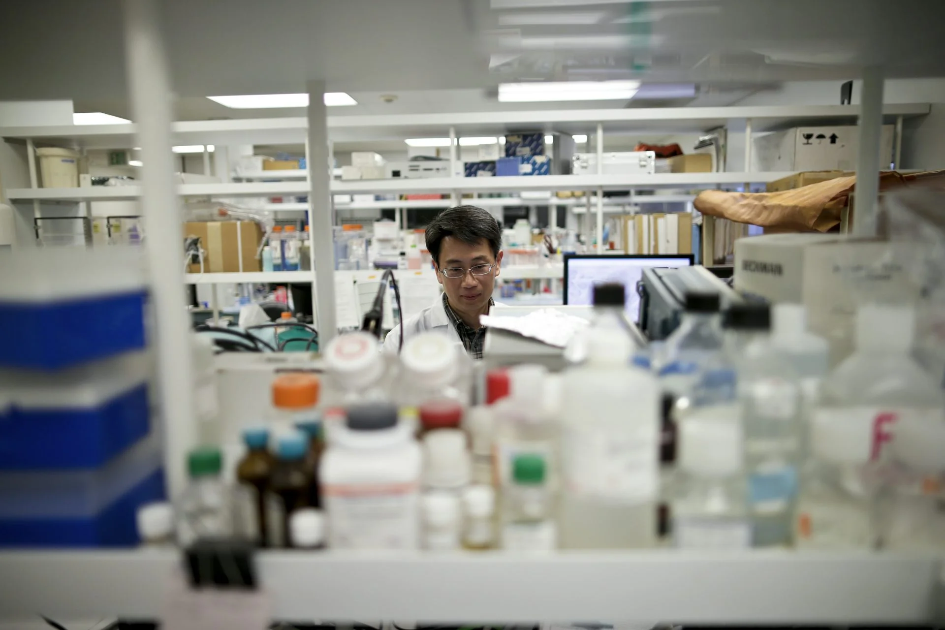 Scientist seen between stacks of lab equipment and materials